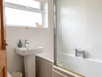 a white bathroom with a sink and a shower at Zephyr's View in Poundstock