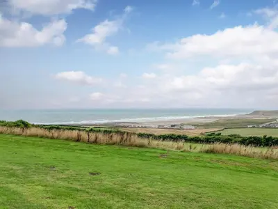 a green field with the ocean in the background at Zephyr's View in Poundstock