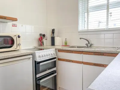 a white kitchen with a microwave and a sink at Zephyr's View in Poundstock