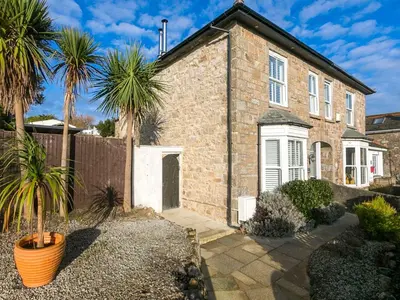a brick house with palm trees in front of it at Ivy Mount in Uny Lelant