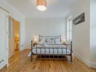 a bedroom with a bed and a wooden floor at Ivy Mount in Uny Lelant