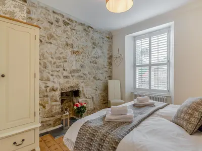 a bedroom with a large bed with a stone wall at Ivy Mount in Uny Lelant