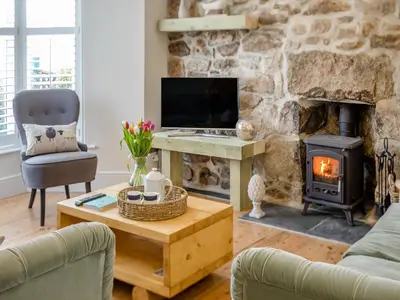 a living room with a stone fireplace and a television at Ivy Mount in Uny Lelant