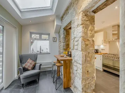 a kitchen with a stone wall and a table and chairs at Ivy Mount in Uny Lelant