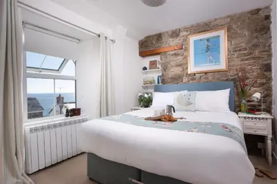 a bedroom with a large bed and a stone wall at Rosevean in Marazion