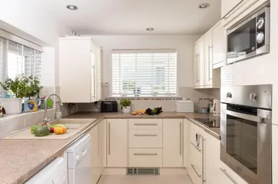 a white kitchen with white cabinets and a sink at Rosevean in Marazion