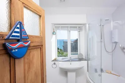 a bathroom with a toilet and a sink with a boat on the door at Rosevean in Marazion