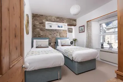 two beds in a room with a stone wall at Rosevean in Marazion