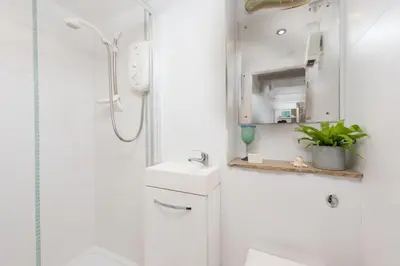 a white bathroom with a shower and a sink at Rosevean in Marazion