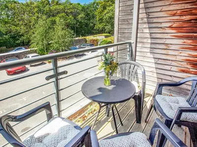 a table and chairs on a balcony with a vase of flowers at 4 Water Wheel Apartment in Charlestown
