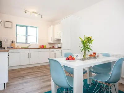a kitchen with a white table and blue chairs at 4 Water Wheel Apartment in Charlestown
