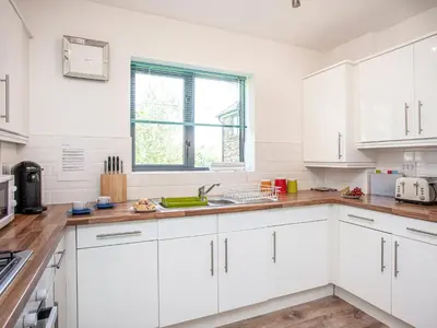 a white kitchen with white cabinets and a sink at 4 Water Wheel Apartment in Charlestown