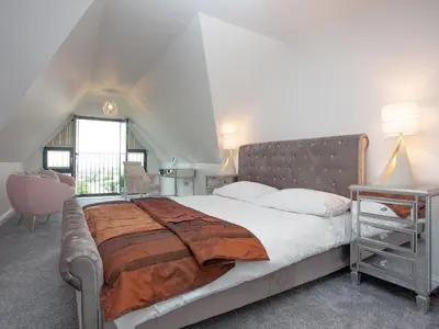a bedroom with a large bed and a window at Pochin House Apartment Penthouse in St Austell