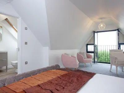 a bedroom with a large bed with pink chairs at Pochin House Apartment Penthouse in St Austell