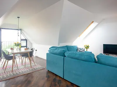 a living room with a blue couch and a table at Pochin House Apartment Penthouse in St Austell