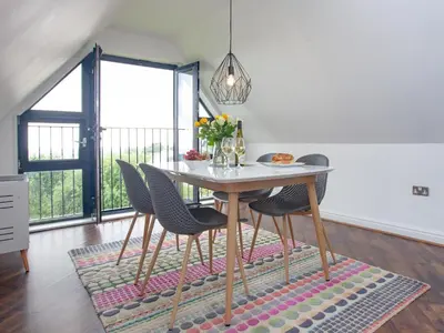 a dining room with a table and chairs on a rug at Pochin House Apartment Penthouse in St Austell