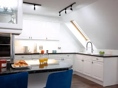 a kitchen with white cabinets and blue chairs at Pochin House Apartment Penthouse in St Austell