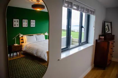 a bedroom with a green wall with a bed and a mirror at Cancleave - Cornish Clifftop Luxury in Bude