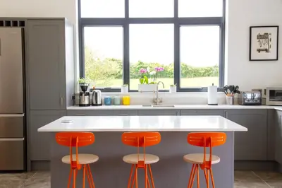 a kitchen with orange bar stools at a kitchen counter at Cancleave - Cornish Clifftop Luxury in Bude