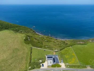 an aerial view of a house on a hill next to the ocean at Cancleave - Cornish Clifftop Luxury in Bude