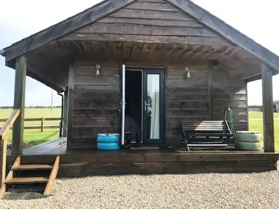 a small wooden cabin with a porch and a door at Hawk's Nest in Wadebridge