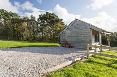 a small building with a fence next to a field at Hawk's Nest in Wadebridge