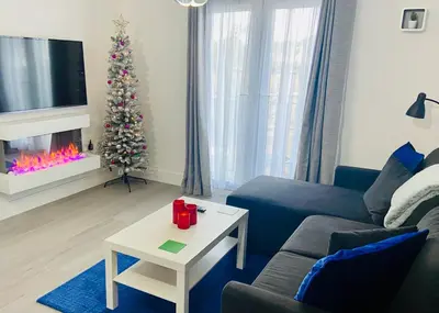 a living room with a christmas tree and a blue couch at Oceano - Carbis bay, St Ives, 1 bed apartment with free parking near to the beach in St Ives