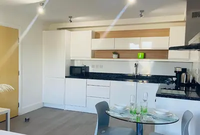 a kitchen with white cabinets and a table with chairs at Oceano - Carbis bay, St Ives, 1 bed apartment with free parking near to the beach in St Ives