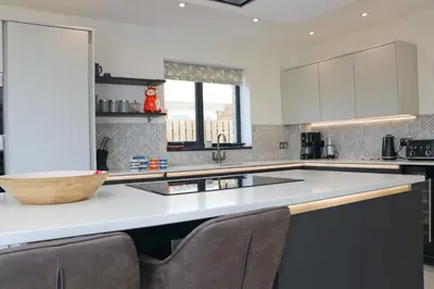 a kitchen with a white counter top with chairs in it at Stunning home, sea views, walk to beach in Saint Ervan