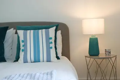 a bed with blue and white pillows and a green lamp at Stunning home, sea views, walk to beach in Saint Ervan