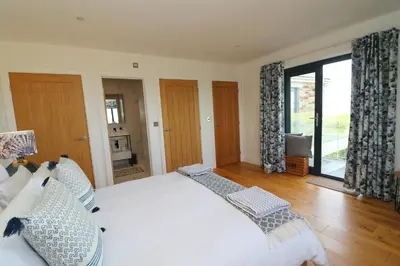 a bedroom with a large bed and a large window at Stunning home, sea views, walk to beach in Saint Ervan