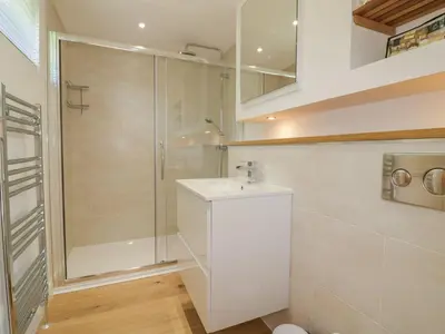 a white bathroom with a shower and a sink at 2 Faraway Fields in Liskeard