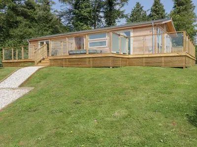 a large wooden house on a grassy field at 2 Faraway Fields in Liskeard