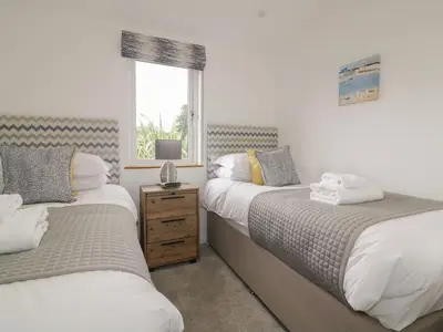 a bedroom with two beds and a window at 7 Faraway Fields in Liskeard