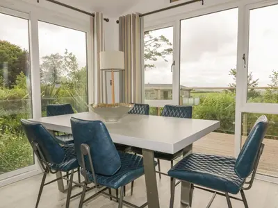 a dining room with a table and chairs and windows at 7 Faraway Fields in Liskeard