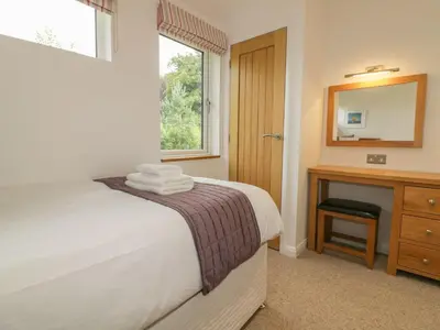 a bedroom with a bed and a dresser and a mirror at 11 Faraway Fields in Liskeard