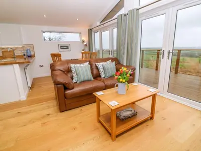 a living room with a brown leather couch and a table at 12 Faraway Fields in Liskeard