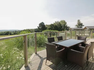 a wooden deck with a table and chairs on it at 12 Faraway Fields in Liskeard