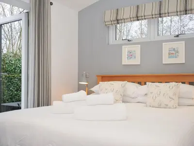 a white bedroom with a white bed with windows at 15 Faraway Fields in Liskeard