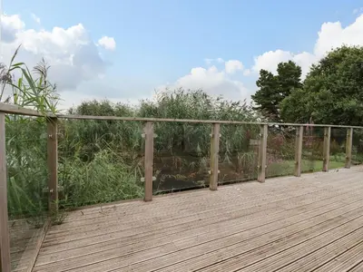 a wooden deck with a fence and some bushes at 15 Faraway Fields in Liskeard