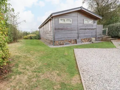 a small house with a grass yard with a building at 15 Faraway Fields in Liskeard