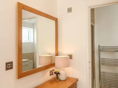 a bathroom with a mirror and a lamp on a dresser at 14 Faraway Fields in Liskeard