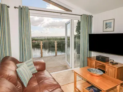 a living room with a couch and a television and a balcony at 14 Faraway Fields in Liskeard