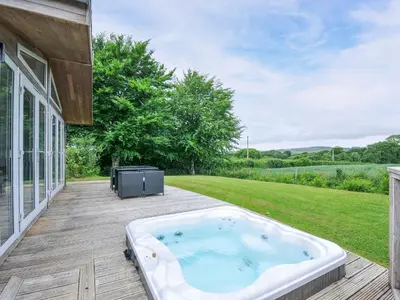 a hot tub on a deck next to a house at 1 Horizon View in Liskeard