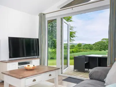 a living room with a tv and a sliding glass door at 1 Horizon View in Liskeard