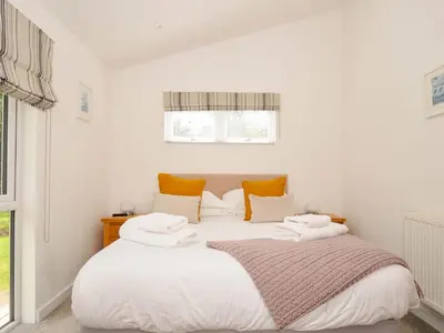 a bedroom with a large white bed with yellow pillows at 3 Horizon View in Liskeard