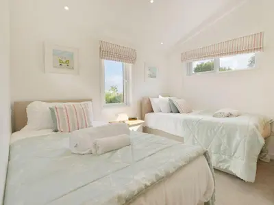 a white room with two beds and two windows at 4 Horizon View in Liskeard