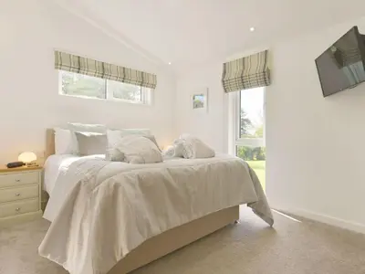 a bedroom with a bed with white sheets and a window at 4 Horizon View in Liskeard