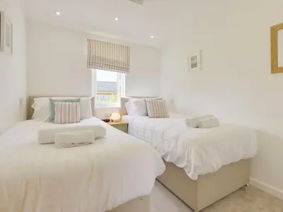 two beds in a room with white walls at 4 Horizon View in Liskeard