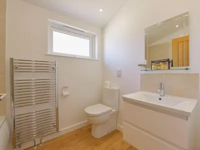 a bathroom with a toilet and a sink and a window at 4 Horizon View in Liskeard